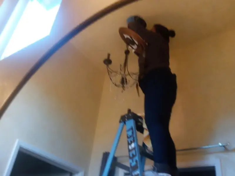 Electrician installing a chandelier in a Manhattan Beach residence